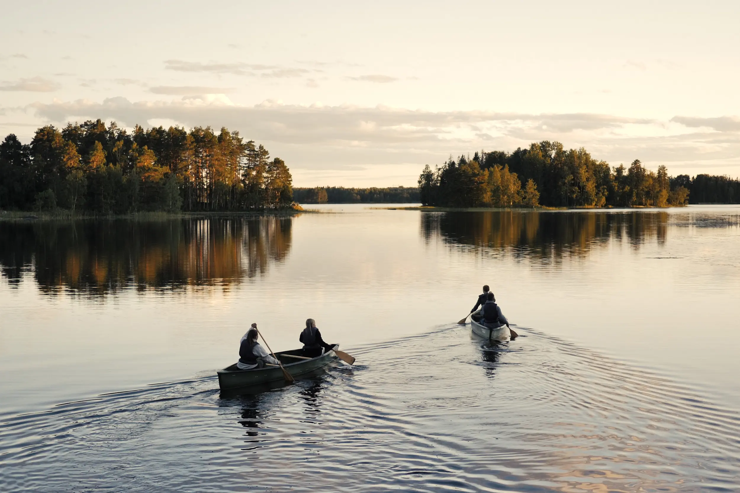 Personer som paddlar i två kanadensare i en sjö